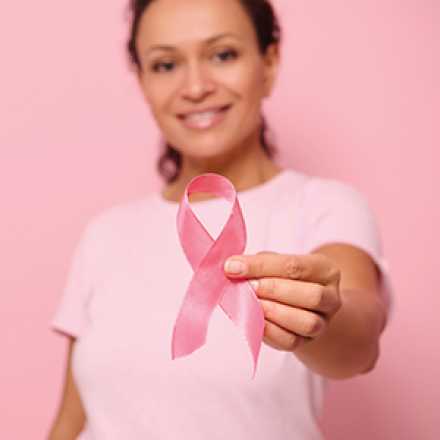 woman dressed in pink holding a pink breast cancer ribbon