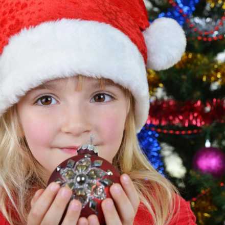 Little girl wearing a santa hat holding an ornament