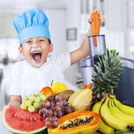 Kid with chef hat on and fruits and veggies in front of him