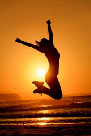 Woman jumping in the air at sunset at the beach
