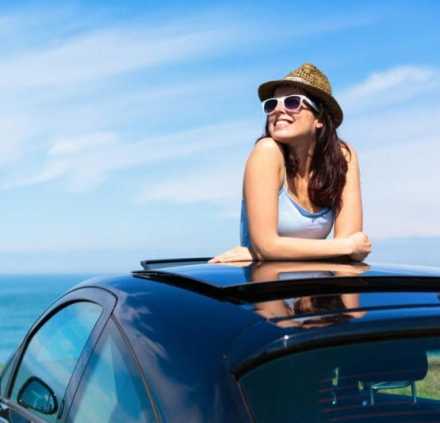 Woman with head out of sunroof at the beach