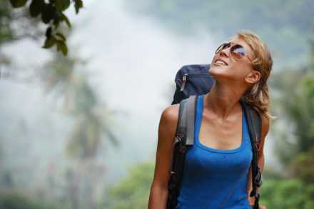 woman walking in the forest with sunglasses and backpack