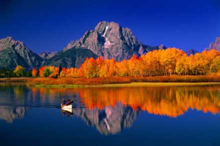 calm Lake with mountains and fall colored forest in the background.