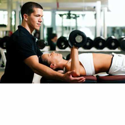 Personal trainer with woman lifting weights