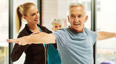 physical therapist helping elderly patient stretch arms