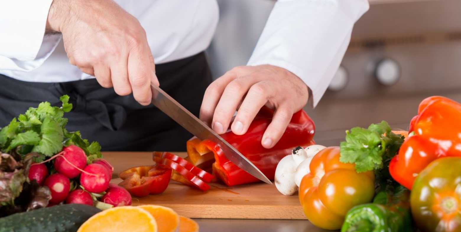 person cutting vegetables on cutting board