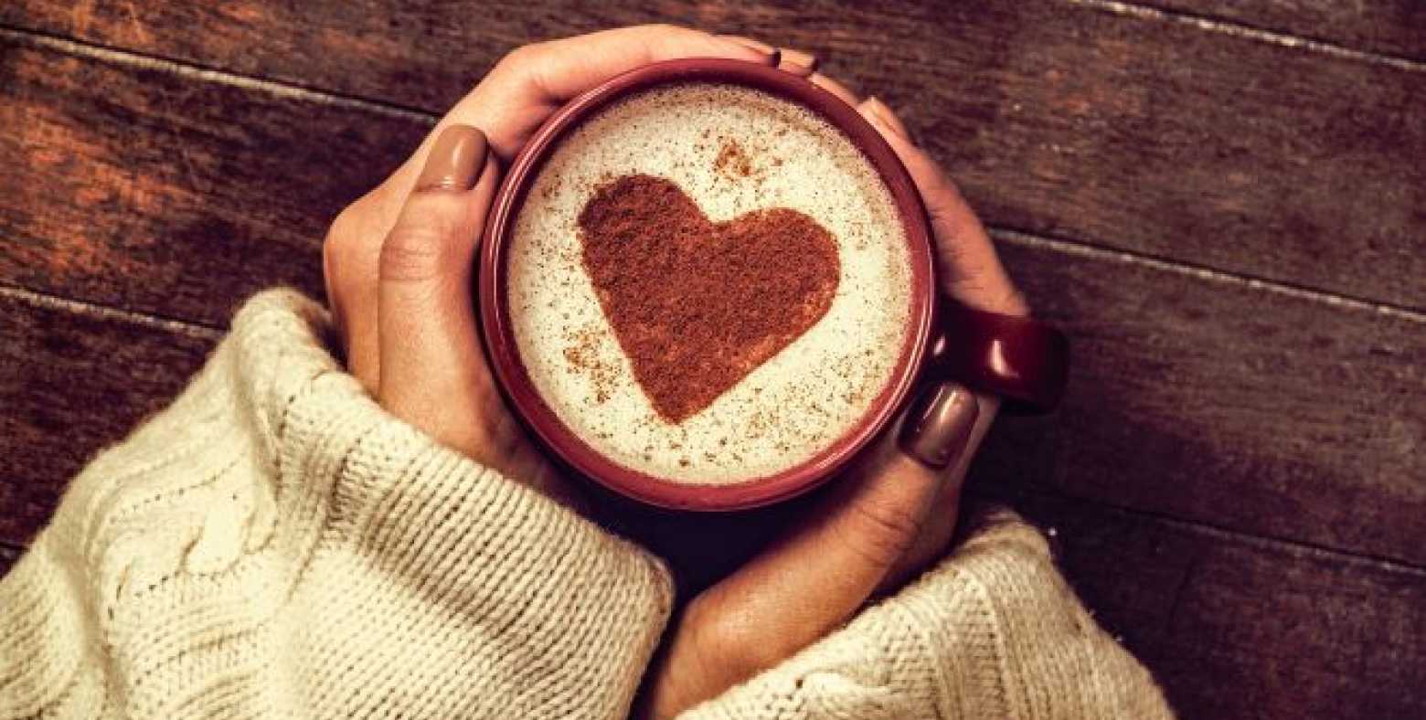 woman's hands holding mug with heart shape art on beverage