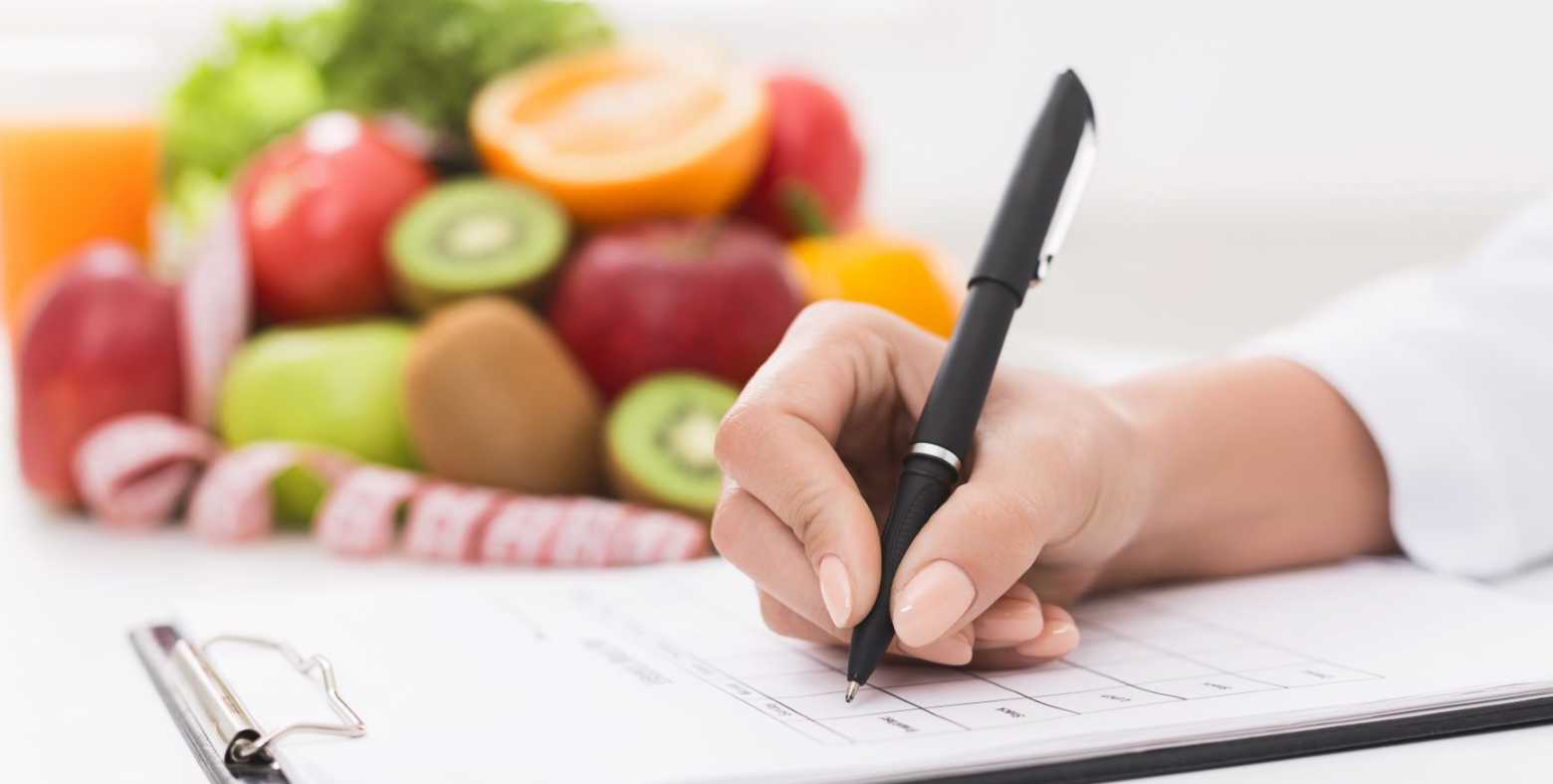 nutrition professional writing notes on clipboard with fruits in background