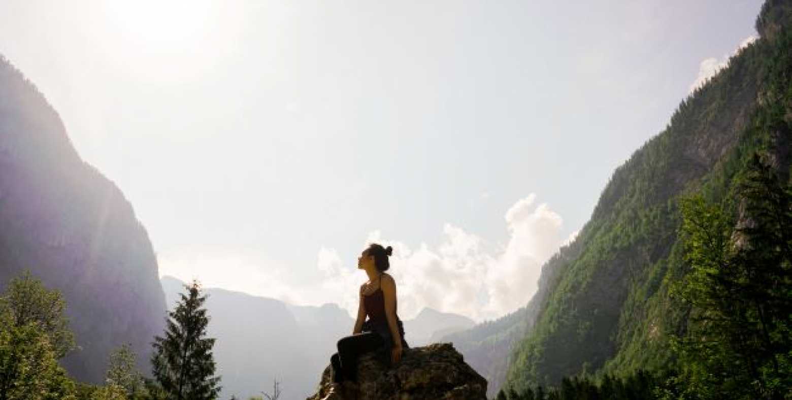 Female sitting on rock gazing at mountains
