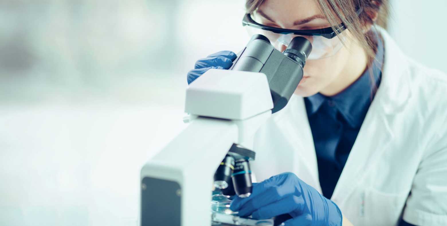female lab worker looking into microscope