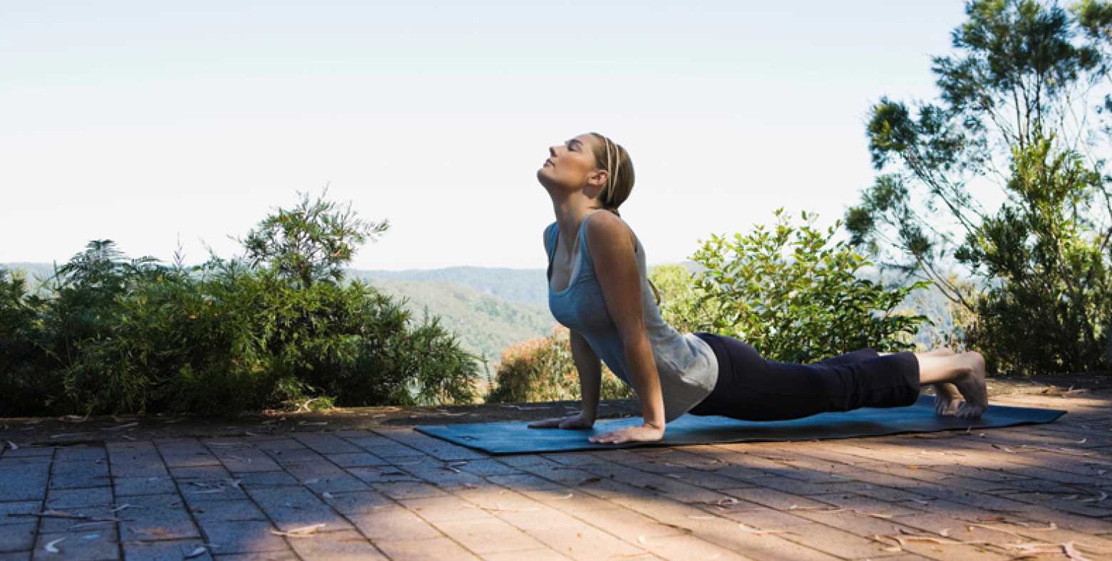 female doing yoga on mat outdoors