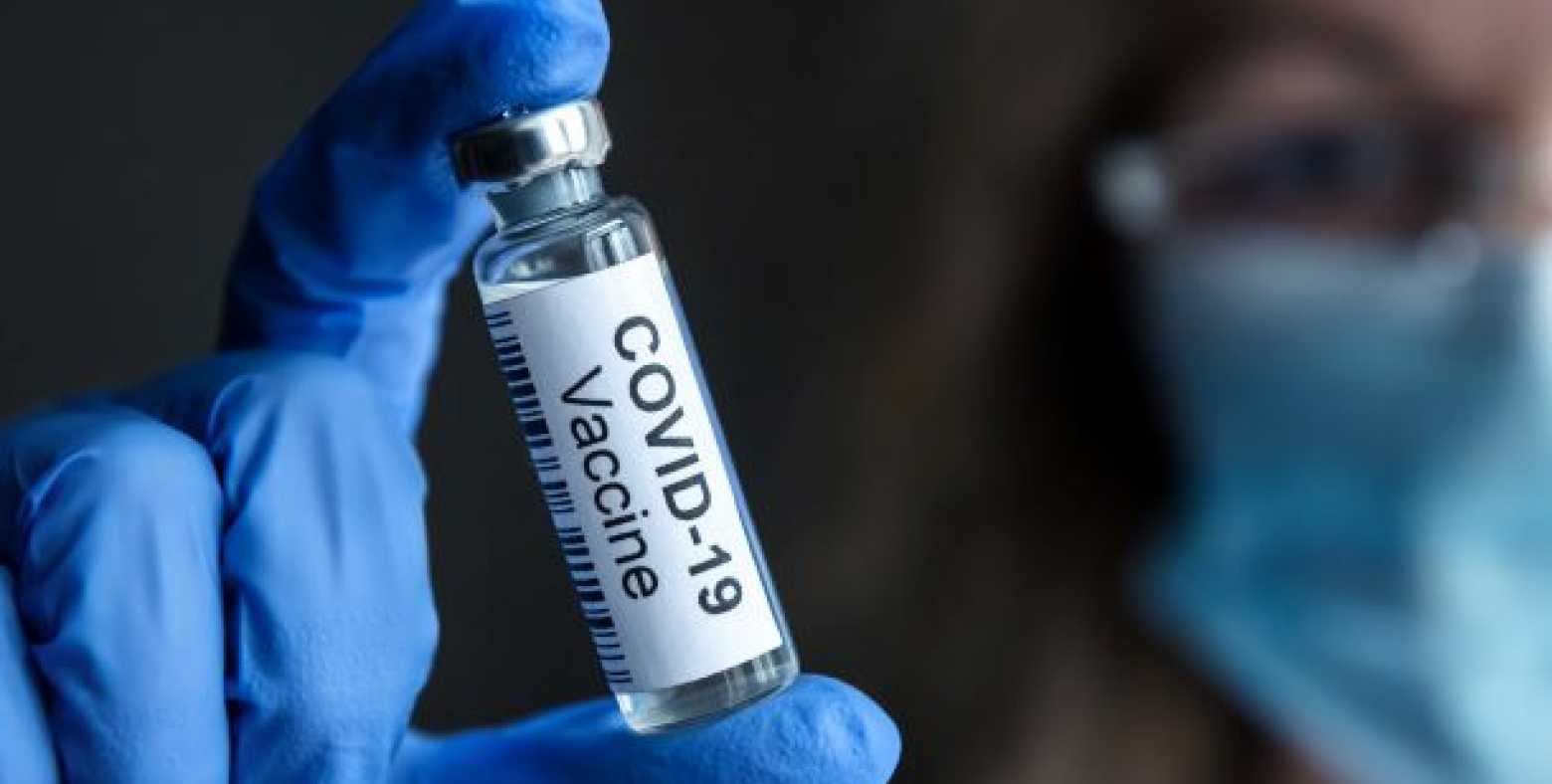 technician holding a vial of covid vaccine