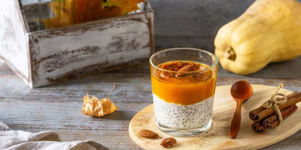 pumpkin chia pudding in a cup with fall decor around  it