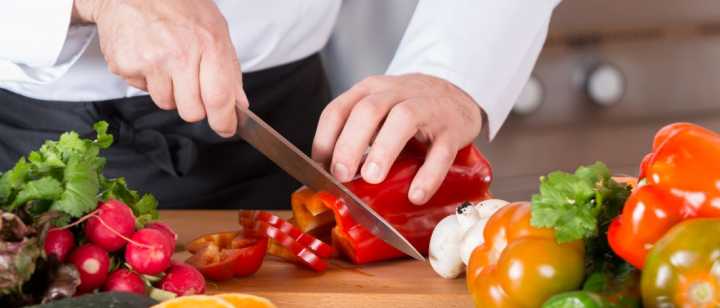 person cutting vegetables on cutting board