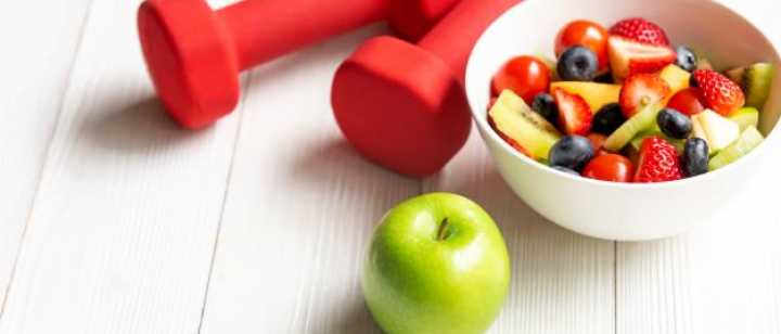 dumbbells, green apple, bowl of cut up fruits