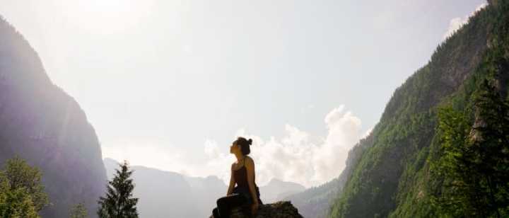 Female sitting on rock gazing at mountains