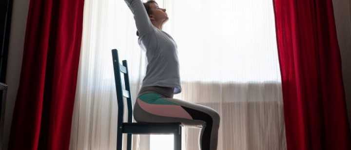 woman doing yoga pose while sittng on chair
