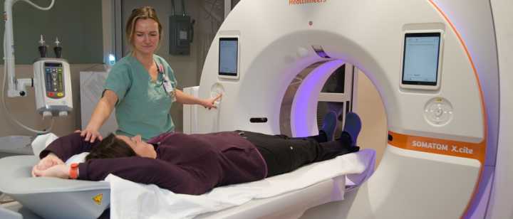 Diagnostic imaging tech with patient and CT scanner