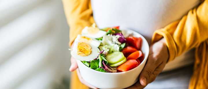 Pregnant woman holding a bowl of salad