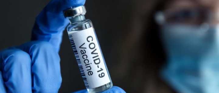 technician holding a vial of covid vaccine