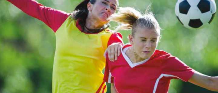 Two women going for a header in a soccer game