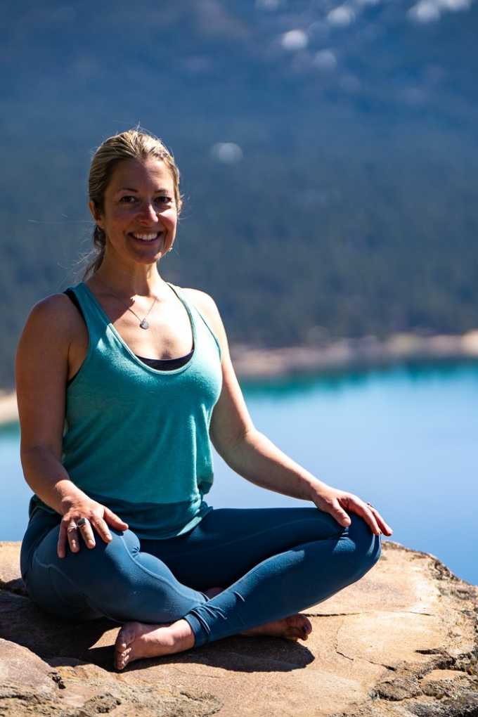 Rachel Durben sitting in yoga pose with Lake Tahoe in background