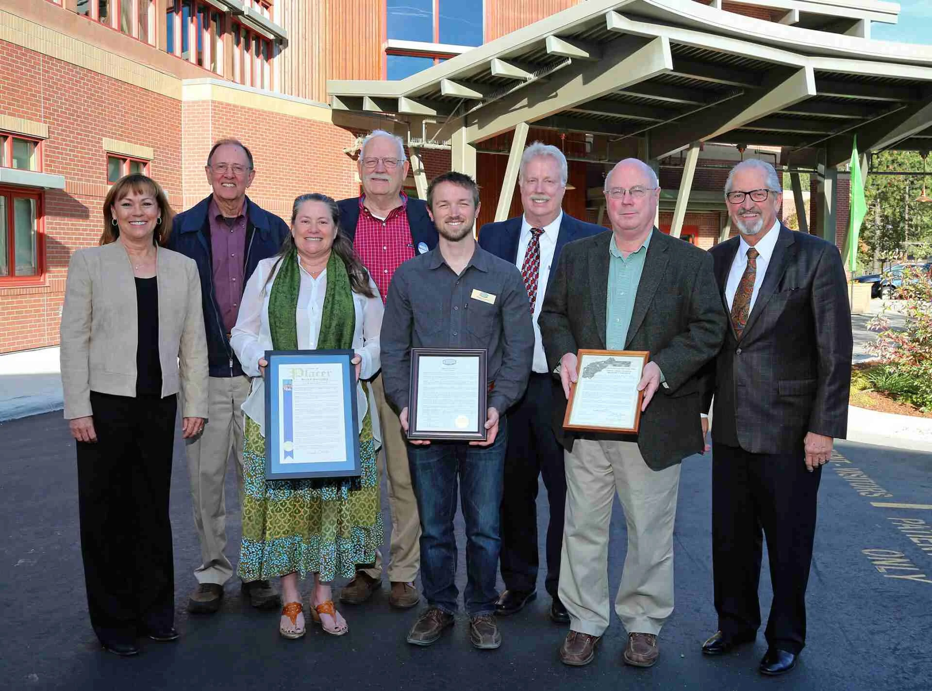 Leadership group holding framed certificates