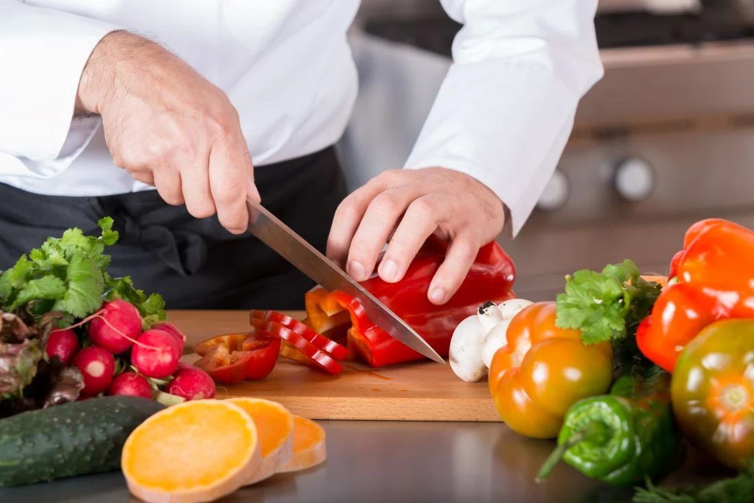 person cutting vegetables on cutting board