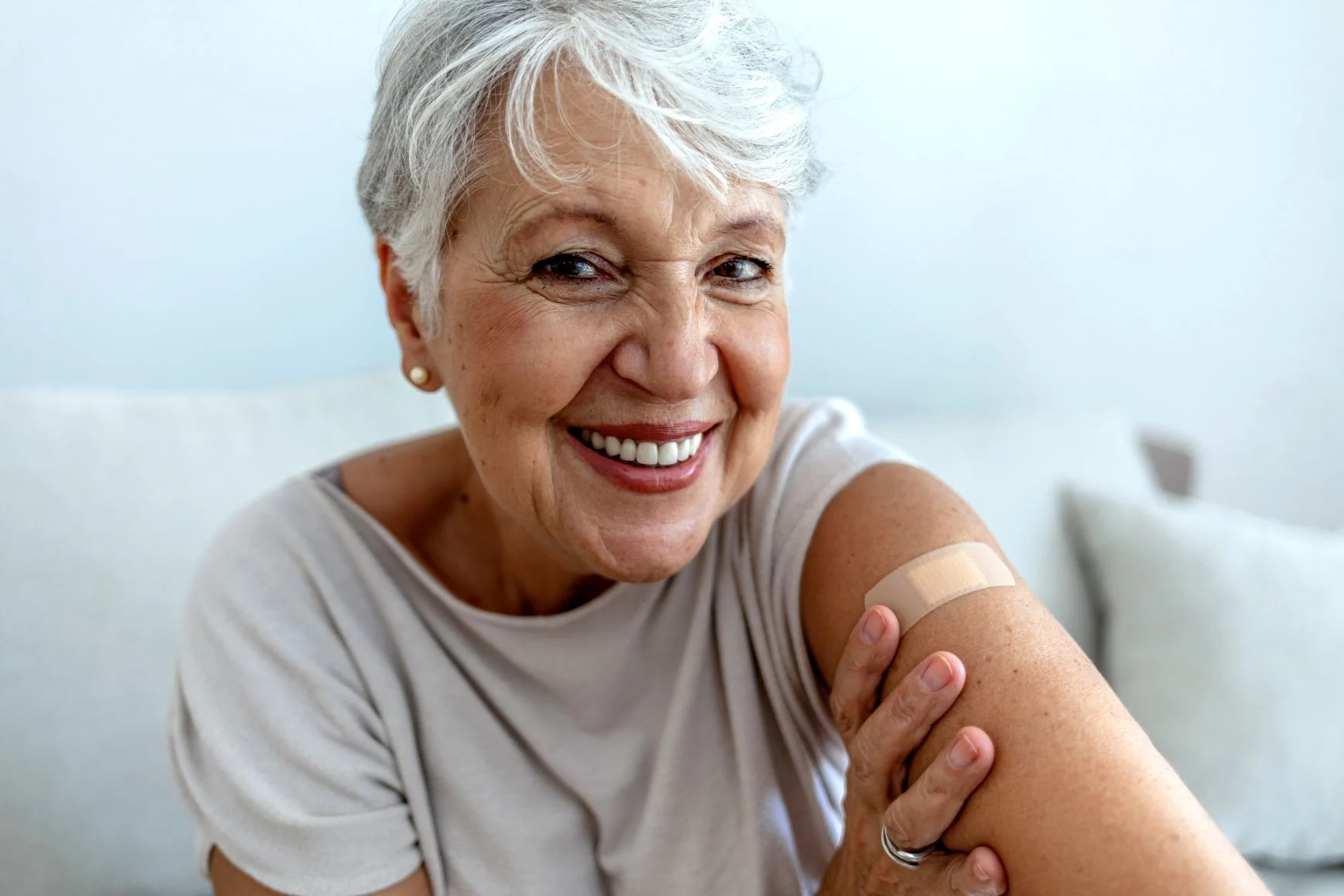 woman wears a bandaid on her shoulder and smiles