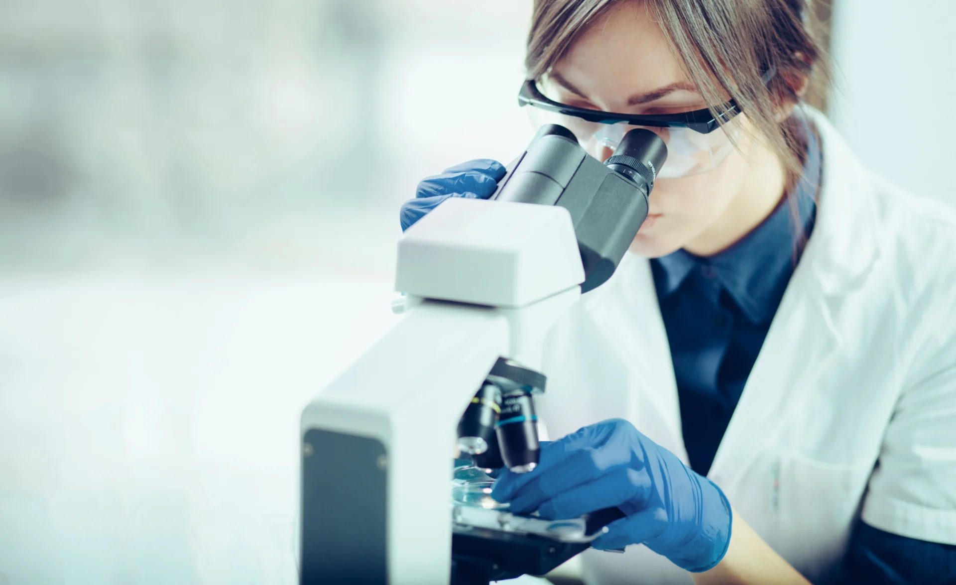 Young scientist looking through a microscope in a laboratory. Young scientist doing some research. lab scientist looking in microscope