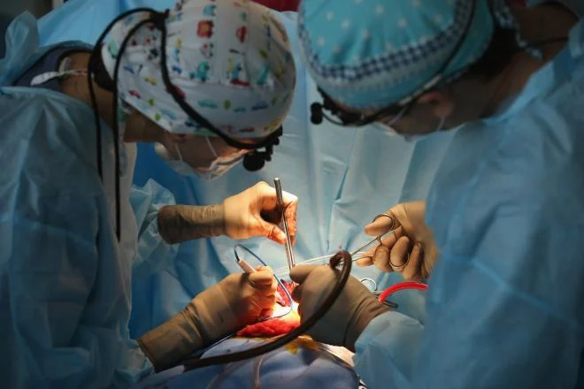 Two doctors performing surgery on a patient