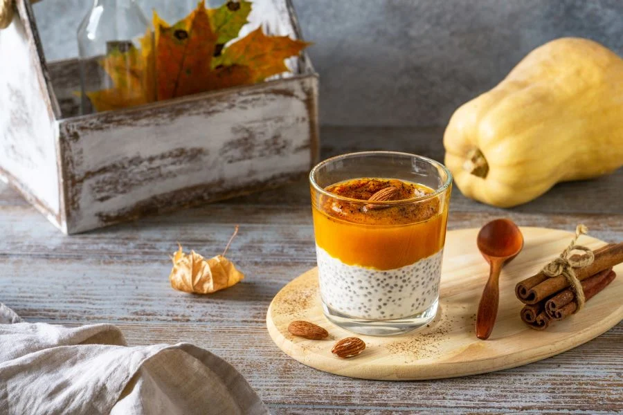 pumpkin chia pudding in a cup with fall decor around it
