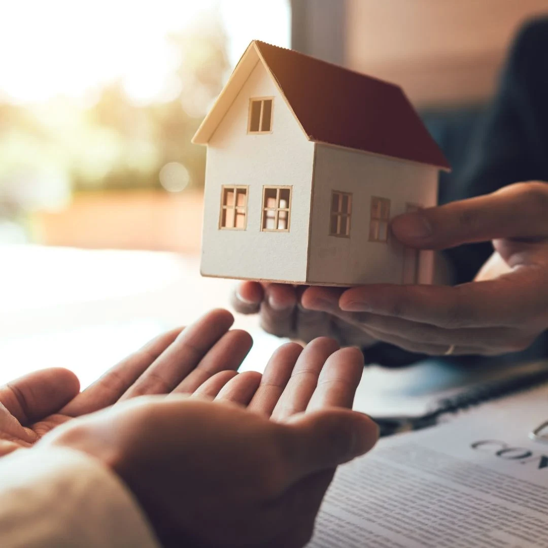 Gift of Real Estate small model home passed from one set of hands to another set of open palms