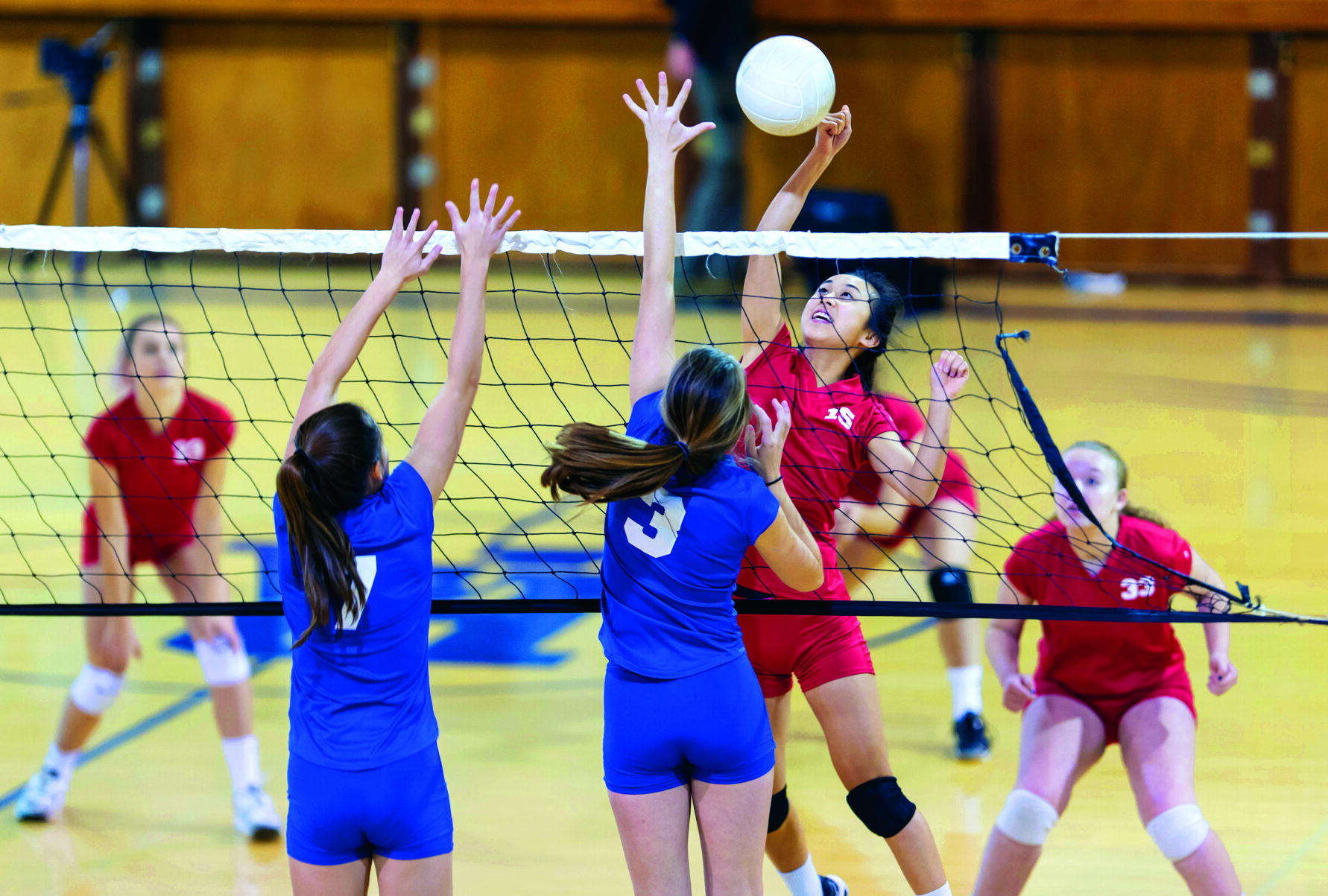 female high school volleyball player spikes volleyball against female opponents Girls volleyball game