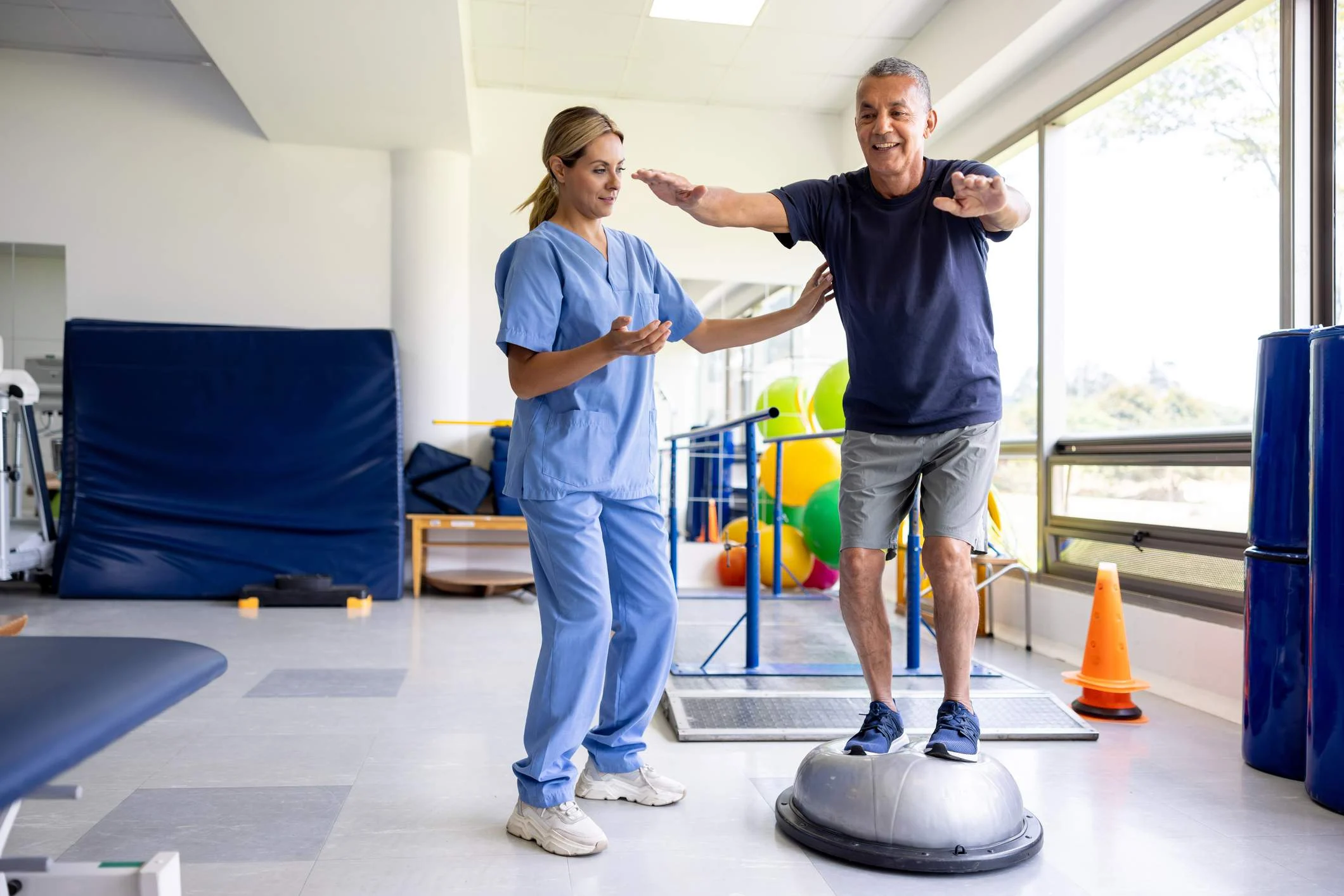 patient balancing on ball while doctor spots
