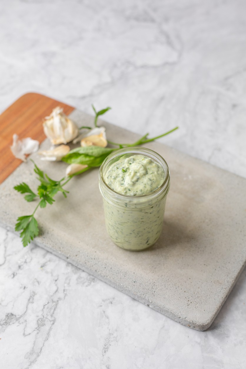 green goddess dressing on cutting board with garlic cloves
