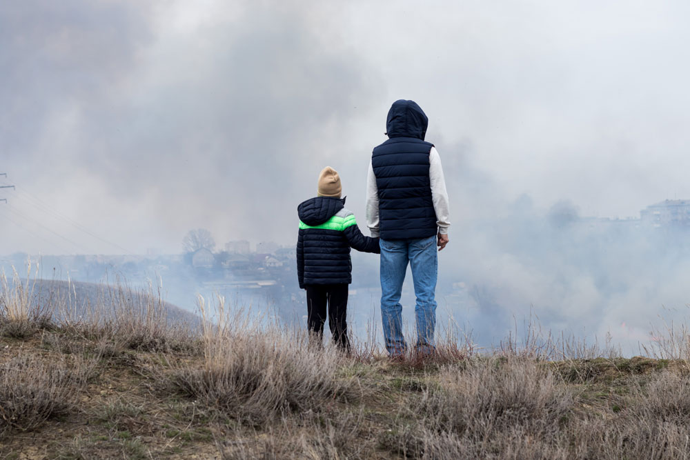 769058148-istock-1421074027 parent and child holding hands watching wildfire smoke