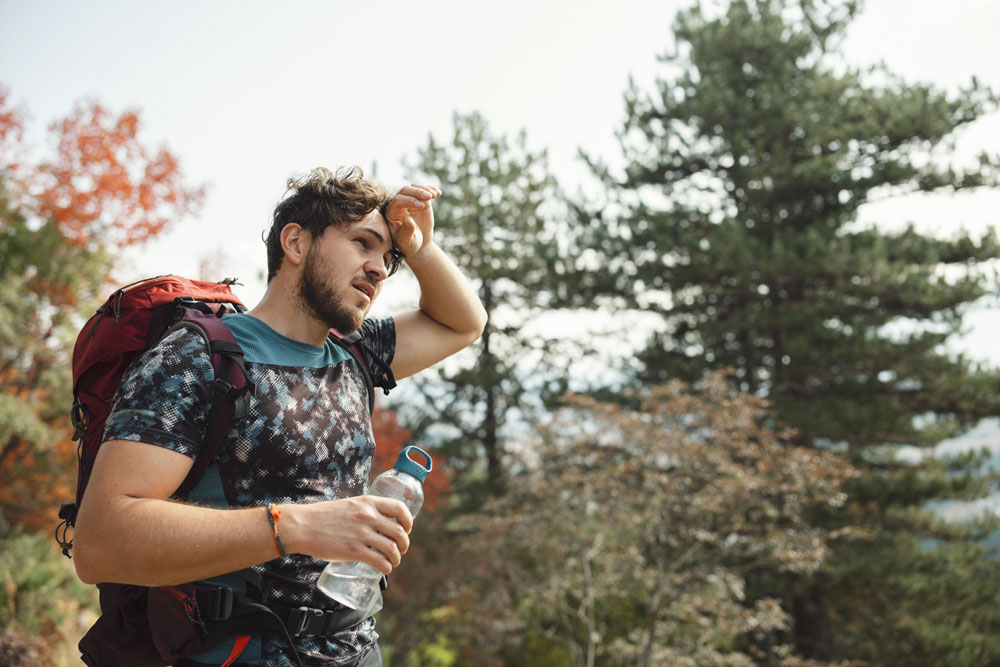 man-hiking-and-hot man hiking rubbing his brow from sweat and heat