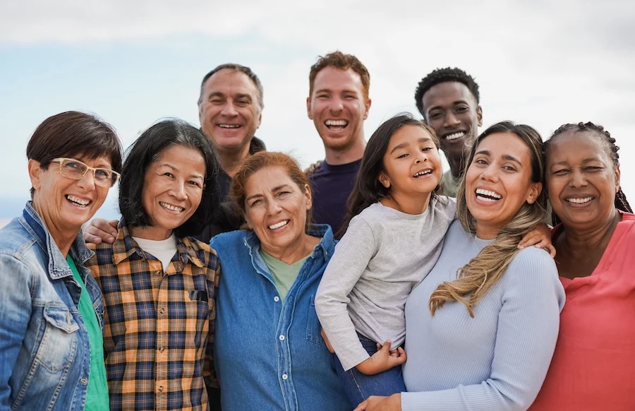 Group of multigenerational people hugging each other while smiling on camera – Multiracial friends having fun together outdoor mutiracial friends hugging and smiling
