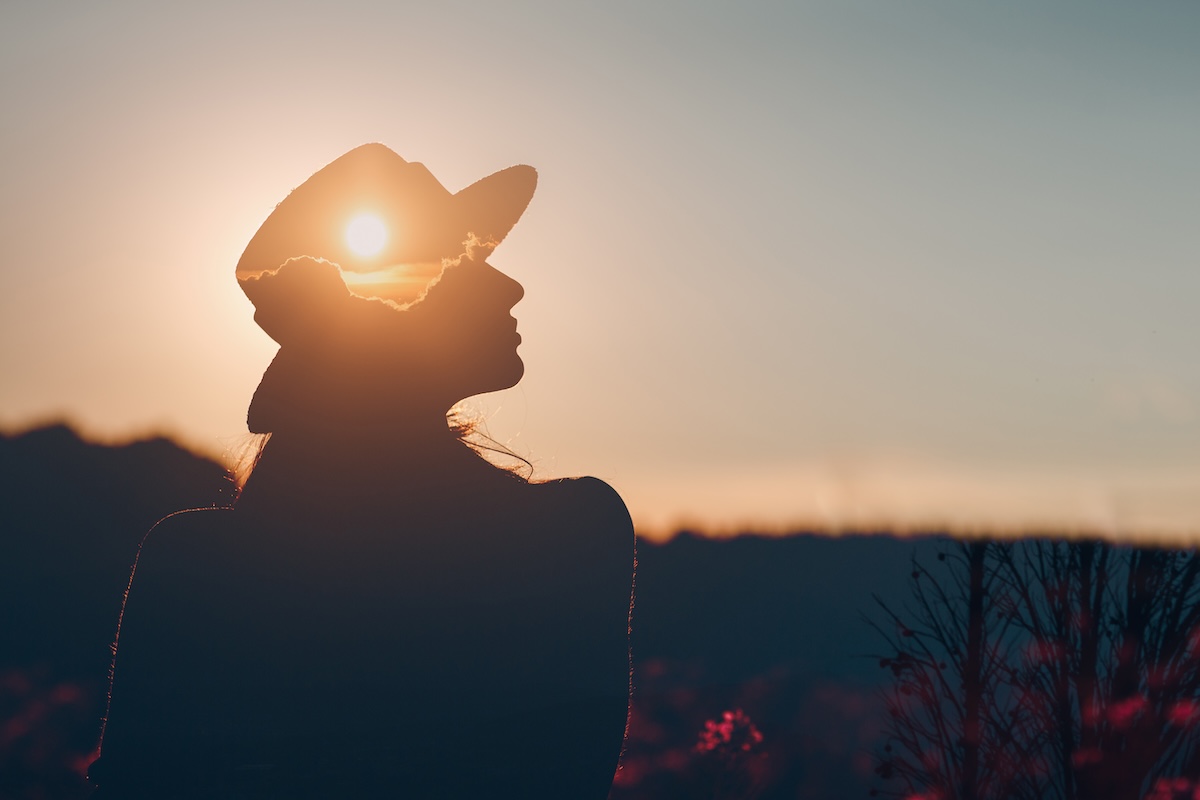 Mental health and business. Silhouette of young adult businesswoman silhouette of female during sunset with sun on her hat