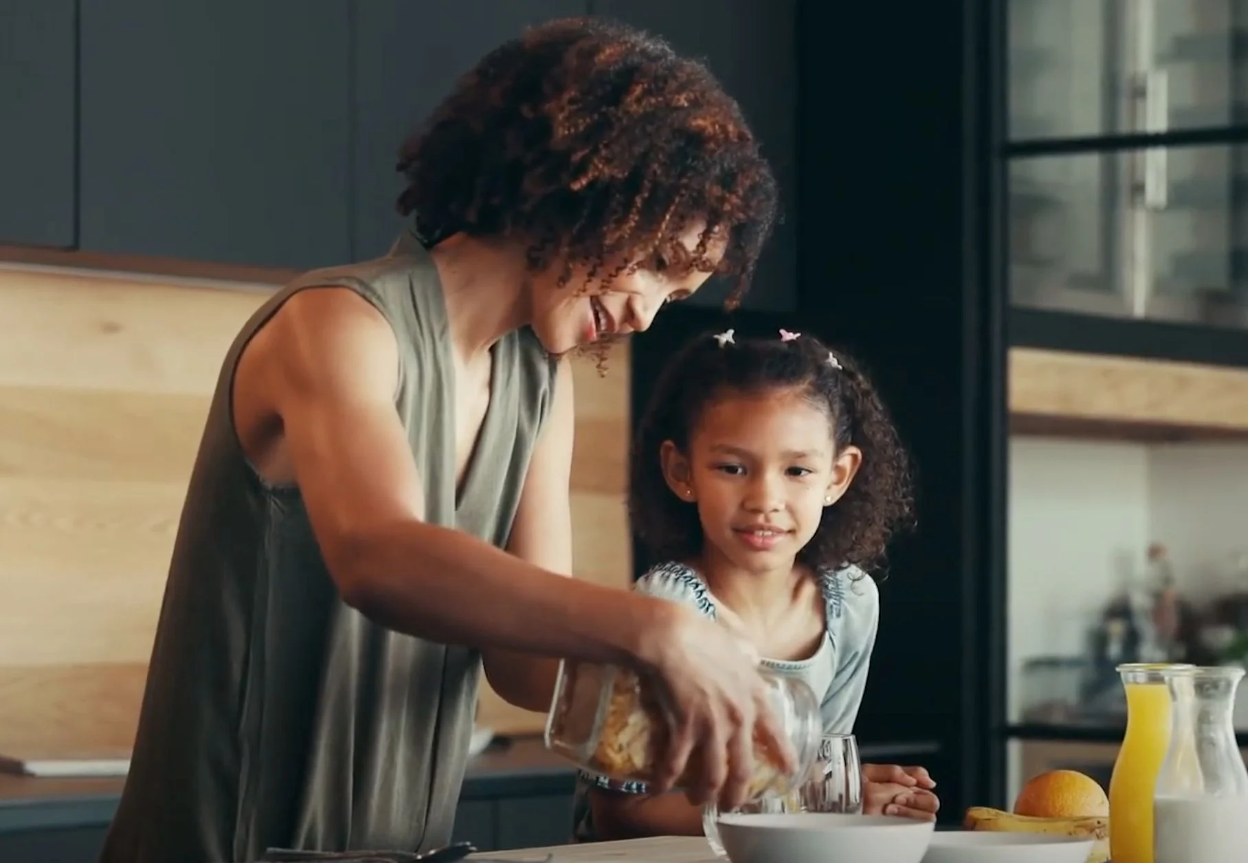 mom with daughter pours granola into a bowl