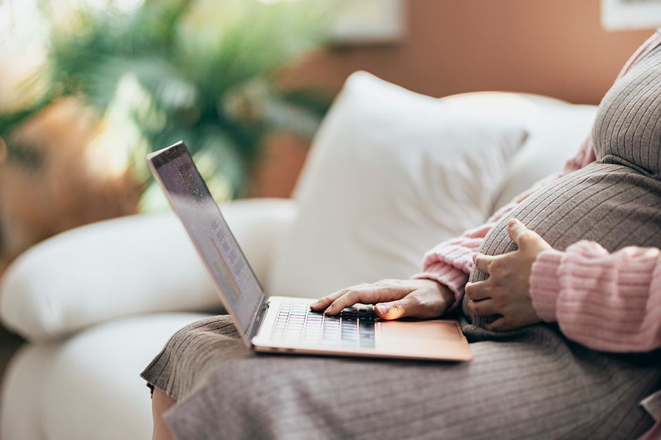 A pregnant woman on a laptop computer