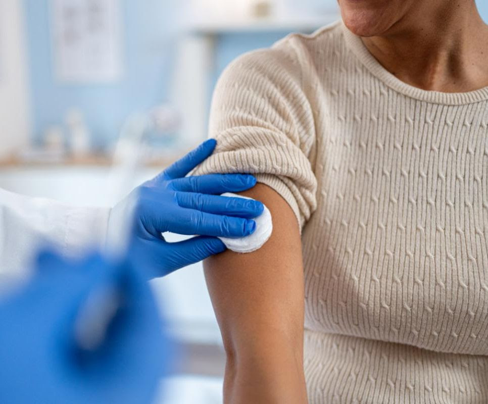 Gloved hands prepare an arm for vaccine