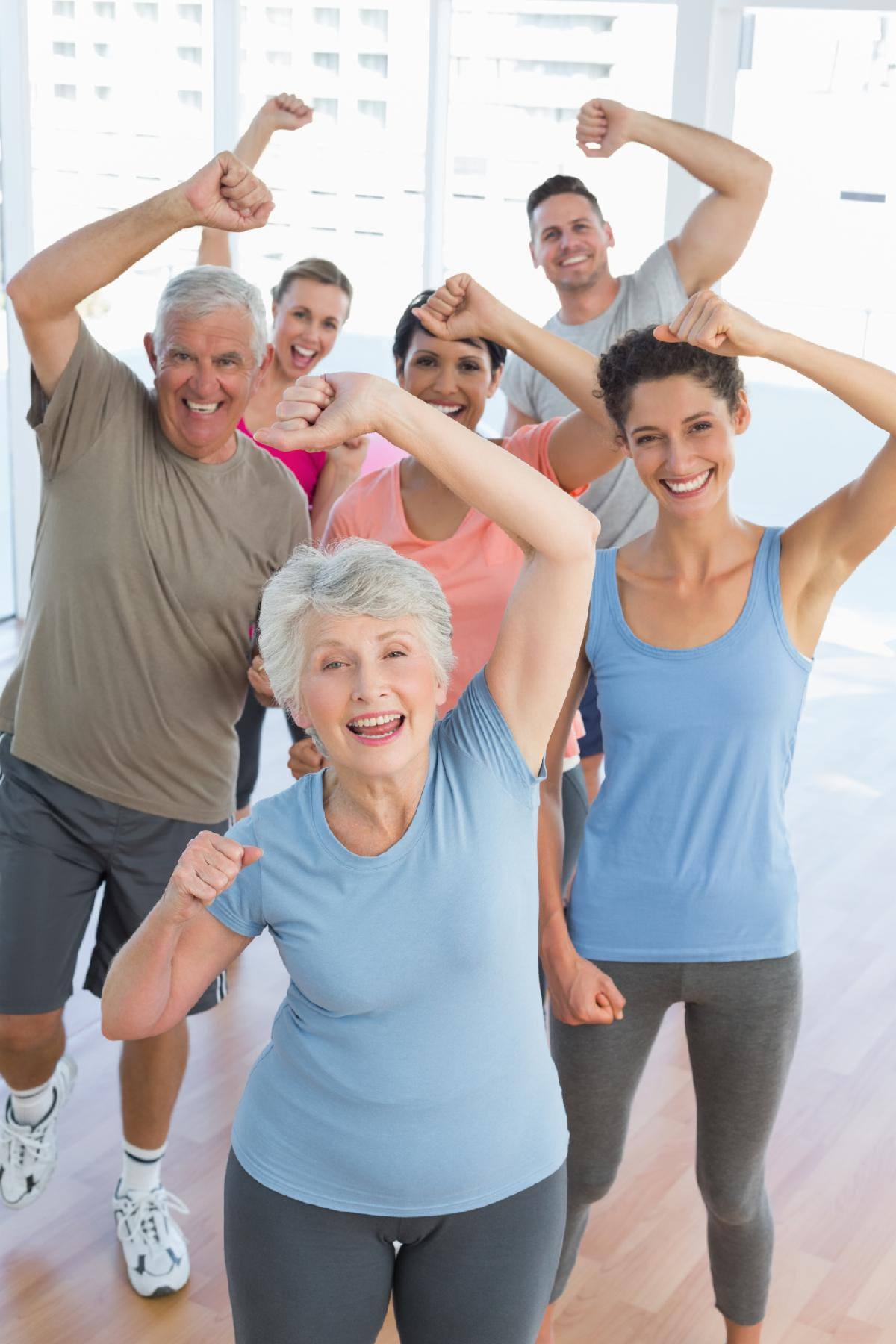 group of exercise goers flex an arm above their heads