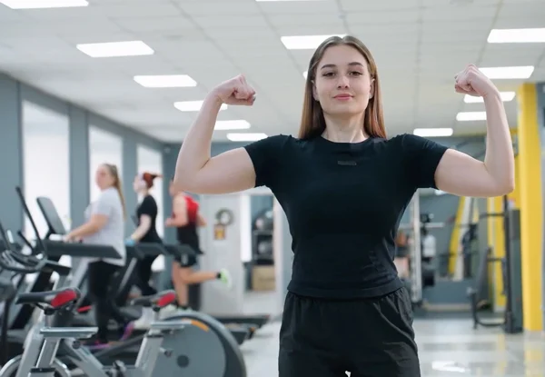 Young woman flexing in the gym