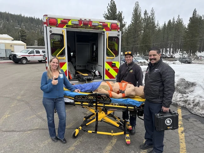 TOM & Truckee Fire (3) TFHS staff member with Truckee Fire personnel with "TOM" by ambulance
