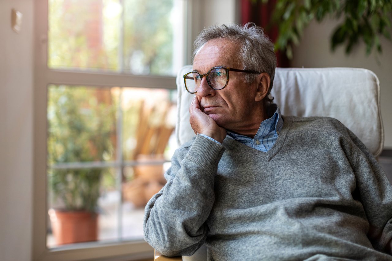 depression older man sits in chair and looks out window