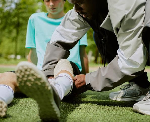 athletic trainer stabilizes knee injury on the field
