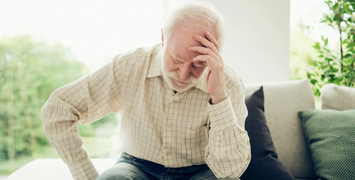 stroke older man leans head on hand