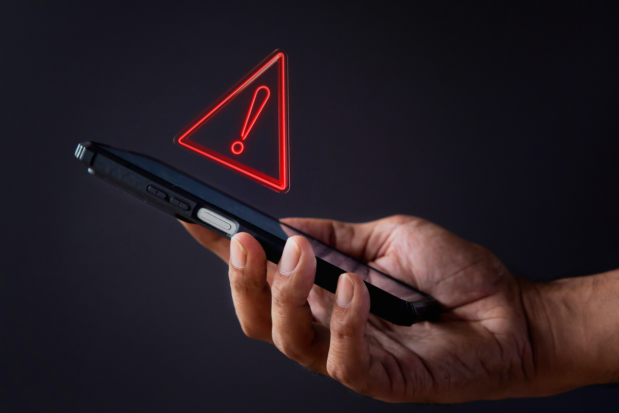 hand holding phone with alert sign